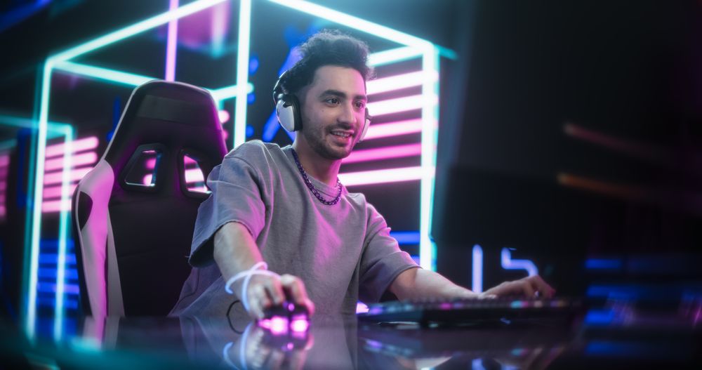 Portrait of a Young Man Putting On Headphones, Talking with Teammates Online During an Intense Computer Match.