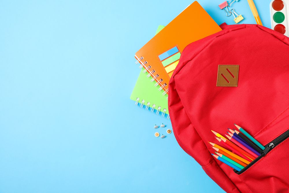 Flat lay composition with backpack and school supplies on color background