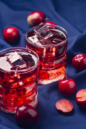 Red beverage near fresh fruits on cloth