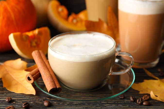 Composition with pumpkin latte, cinnamon and pumpkin on wooden background