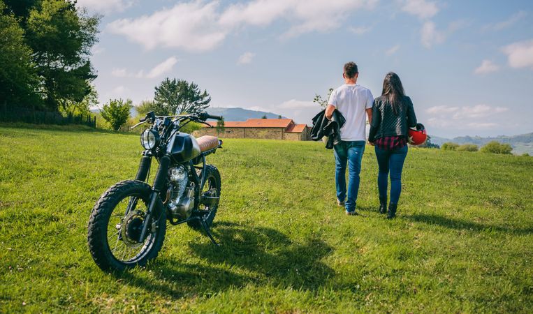 Couple walking on the field holding hands and motorbike