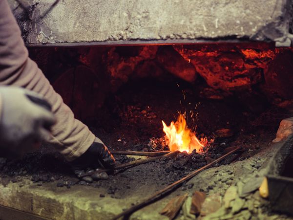 Blacksmith heating iron in hot furnace
