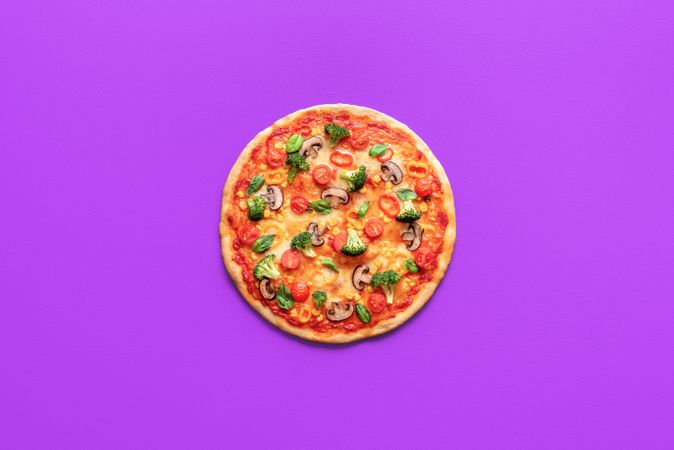 Homemade vegan pizza isolated on a purple background, top view