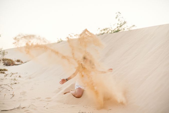Woman having fun throwing sand in desert