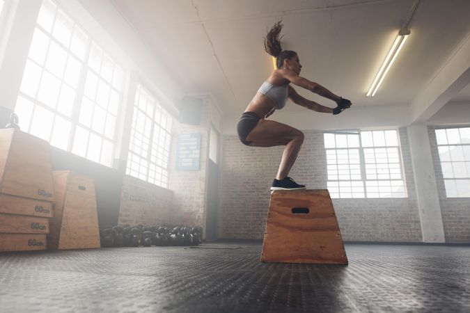 Side view image of fit young woman doing a box jump exercise