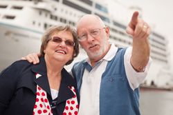 Older Couple On Shore in Front of Cruise Ship