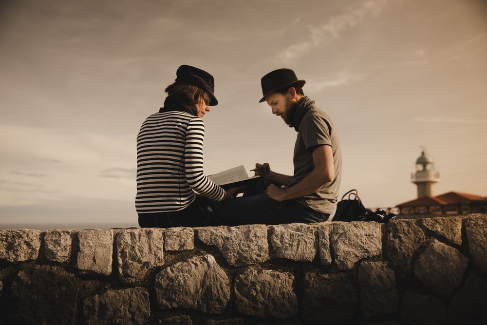 Man and woman on stones near lighthouse