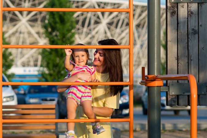 Toddler girl and mother playing at bars outside