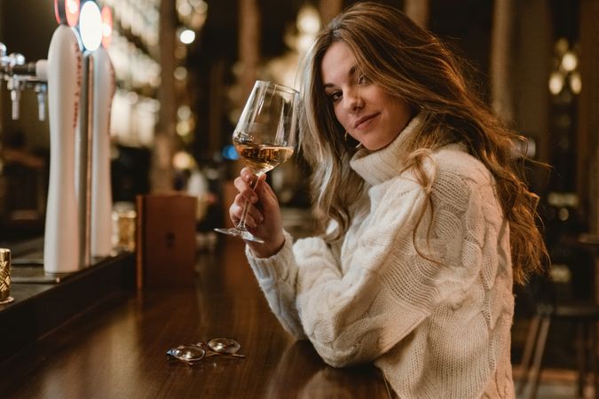 Stylish woman drinking wine in bar