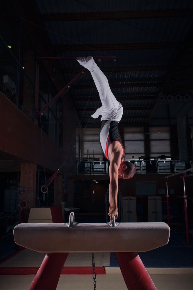 Young male gymnast doing exercises on the rack