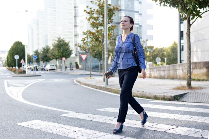 Smiling businesswoman crossing road in city