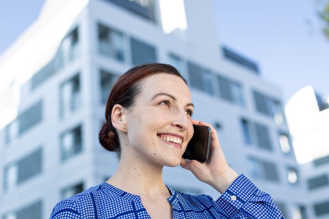 Serious manager speaking on phone on street
