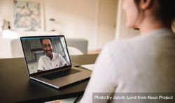 Woman sitting at table having a video call with her husband on laptop 0KPMD5