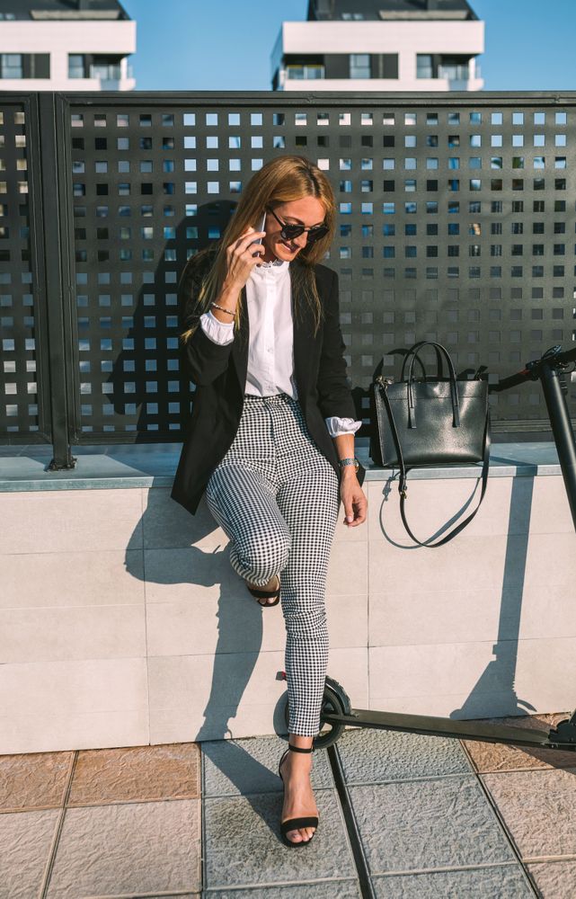 Businesswoman with mobile and her scooter next