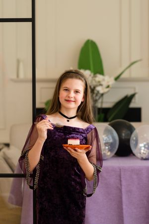 Girl smiling while eating cake at birthday party.