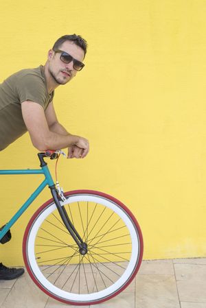Male leaning over bike in front of yellow wall