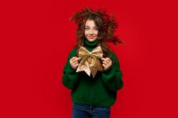 Young girl in green sweater holding large golden glittery bow