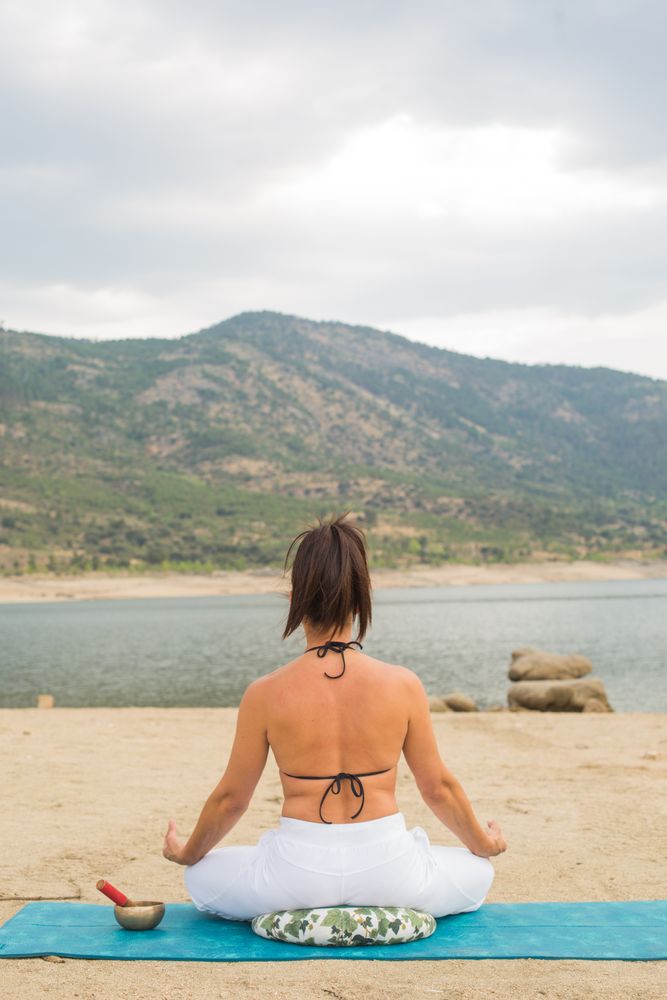 Woman practicing yoga outdoors near water