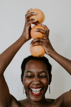 Woman holding orange fruit over her head smiling