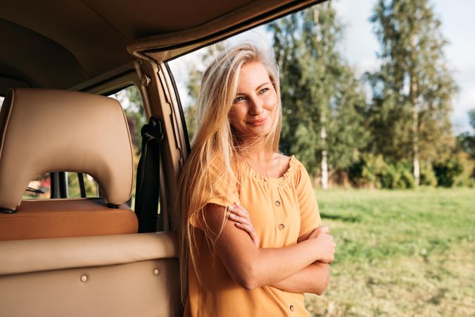 Blonde woman leaning on a van door in a field