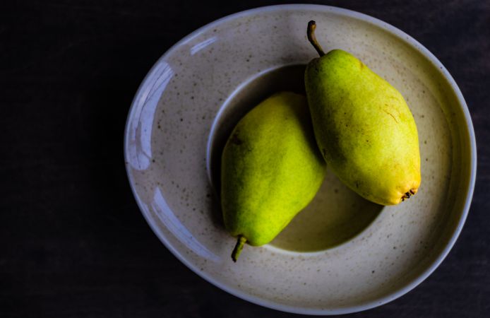 Two organic ripe pears in grey bowl