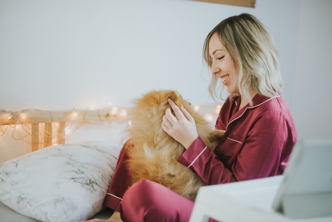Smiling woman sitting in bed with dog