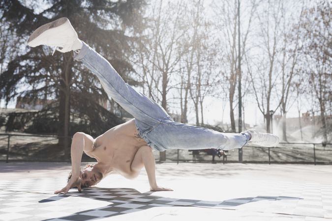 Shirtless man dancing break dance in park