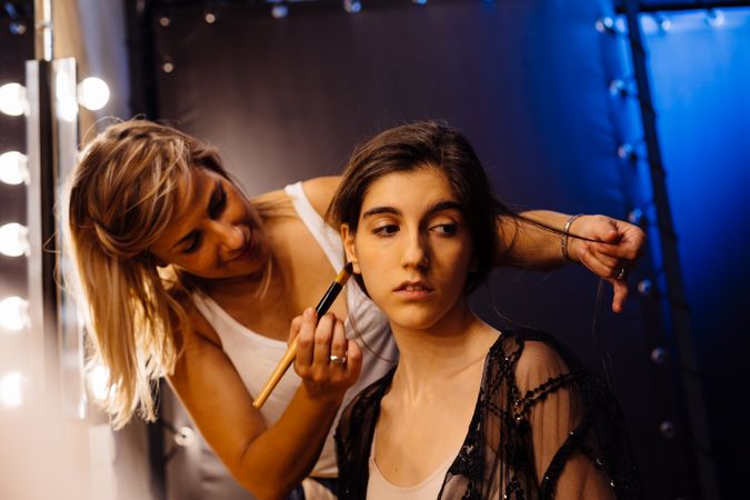 Makeup artist doing makeup for young female artist