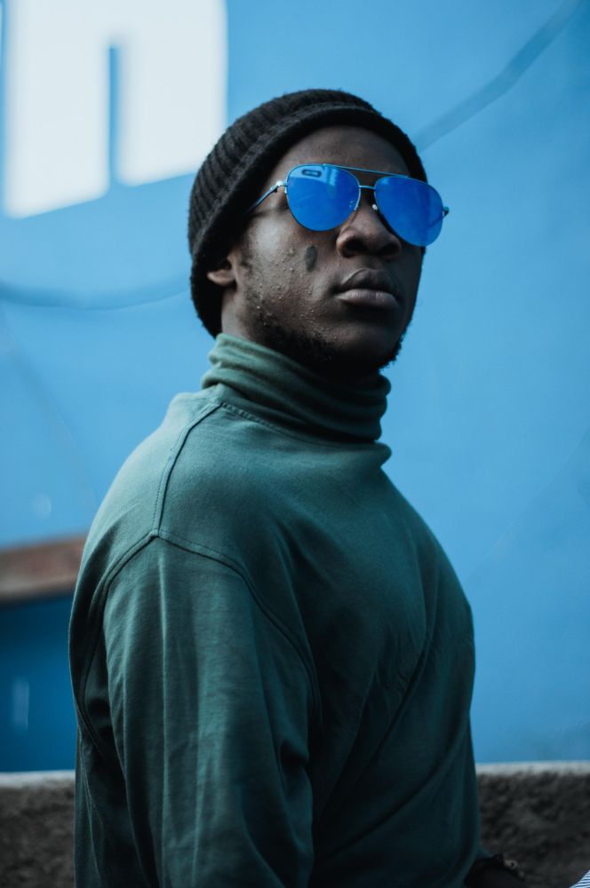 Man wearing turtle neck top, beanie and sunglasses