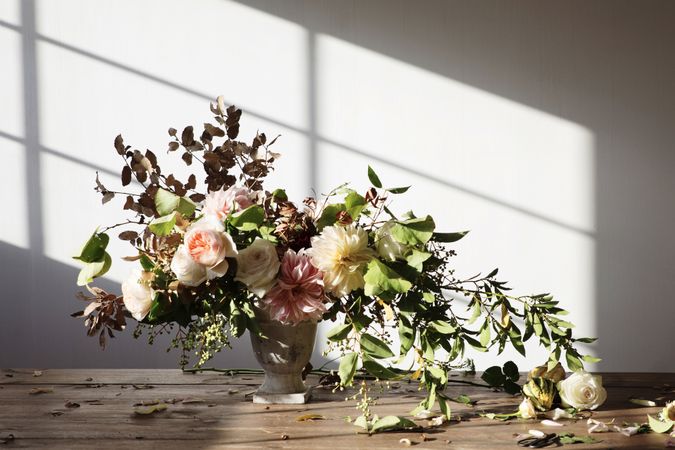 Composition of flowers and plants in vintage vase on board