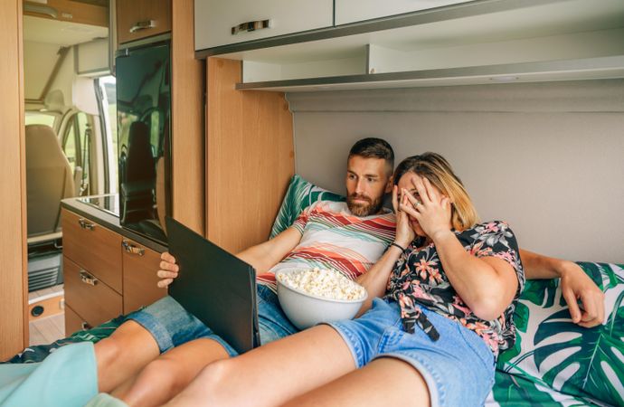 Male and female watching a shocking film on a digital tablet on a motorhome bed