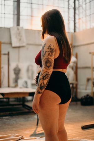Back view of tattooed woman in dark panty and red brassiere