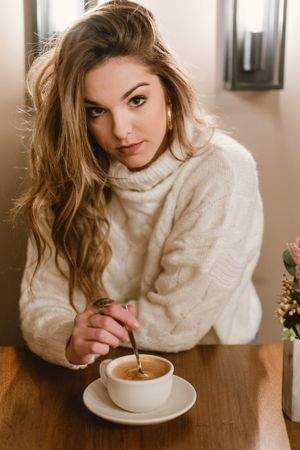 Elegant woman mixing coffee in cafe