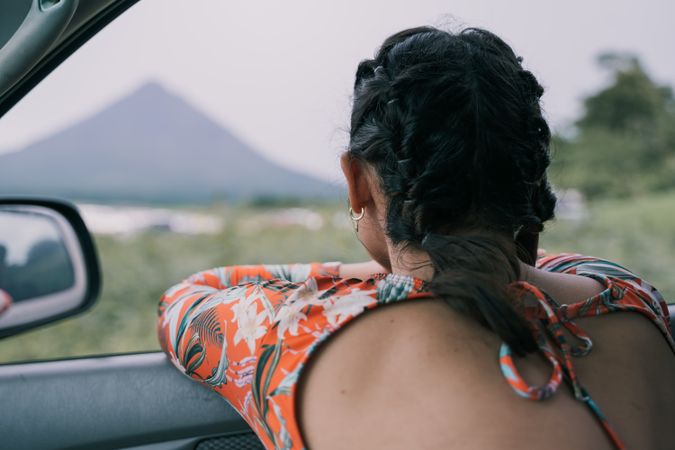 Backside of women in orange top looking out of car window