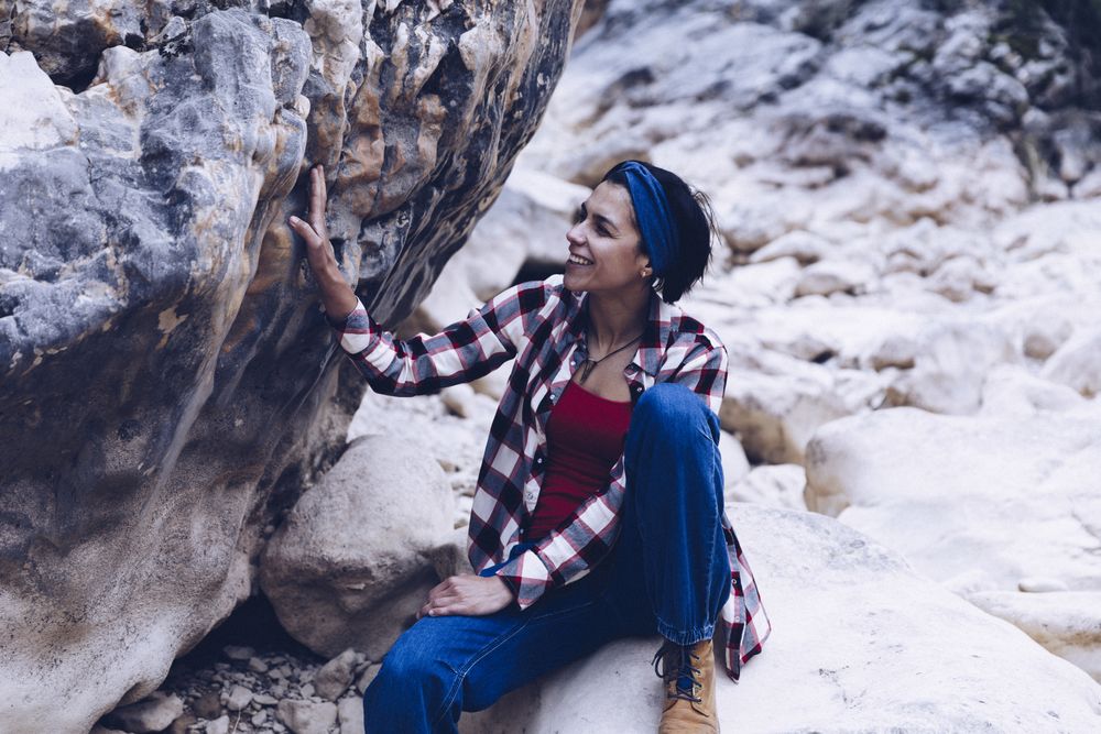 Positive woman sitting on stone
