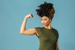 Studio shoot of Black woman smiling flexing her bicep