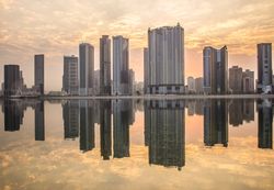 City skyline across sea in Sharjah, UAE at sunset 4jz6R4