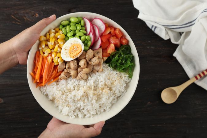 Female hand Holding Big Bowl with Poke Bowl, Hawaiian Rice with Various Topping