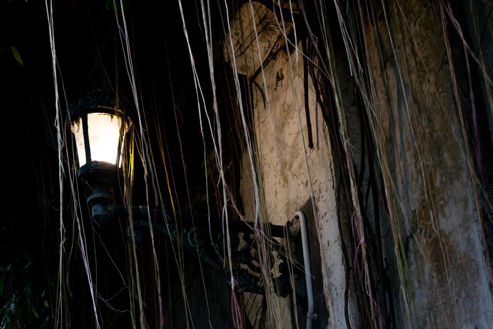 Vintage street lantern hanging on the old wall in creepy dark night