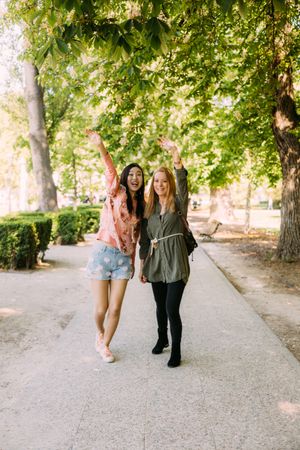 Cheerful multiethnic women greeting friend in park