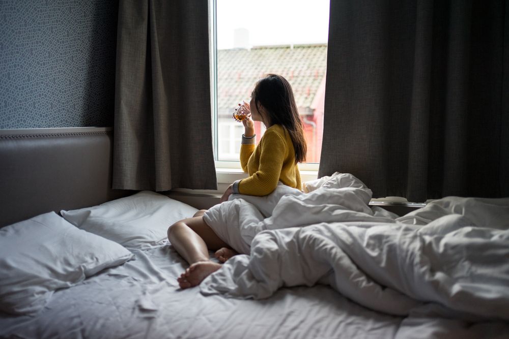 Anonymous female on vacation delighting in view in window while drinking tea in morning
