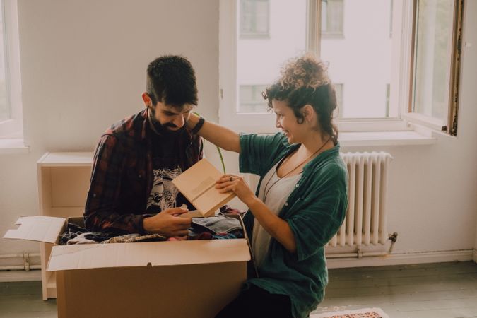 Couple having fun while unpacking boxes at home