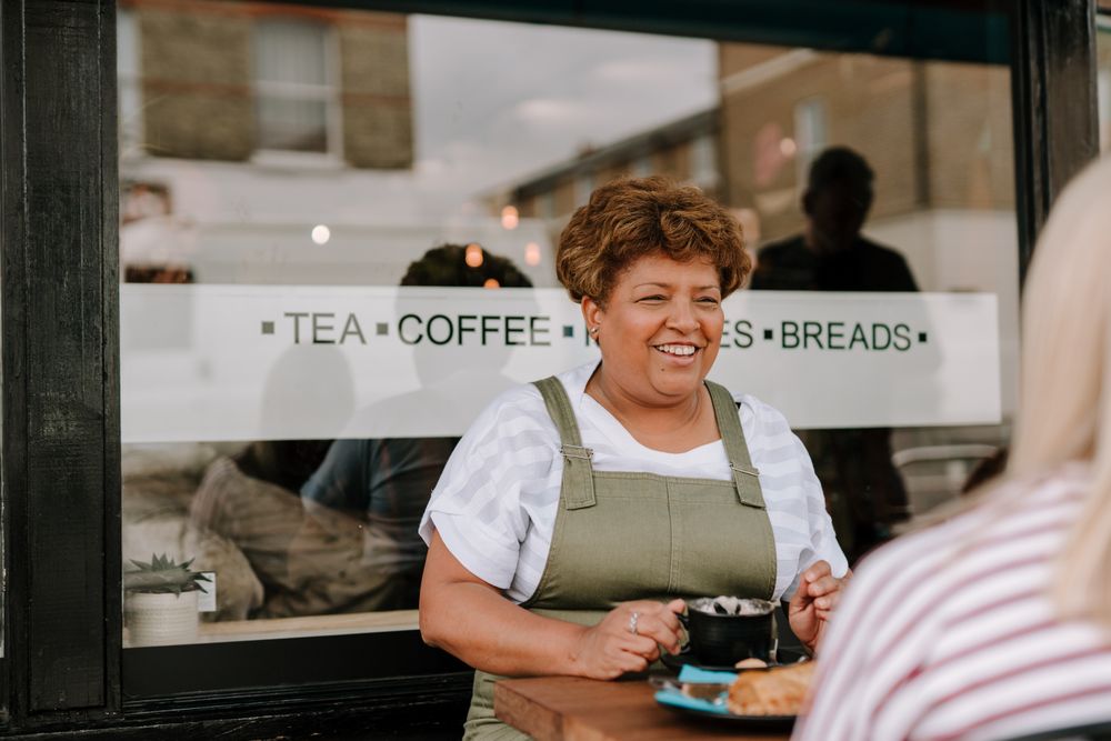 Older Black woman with coffee and friends at outdoor table