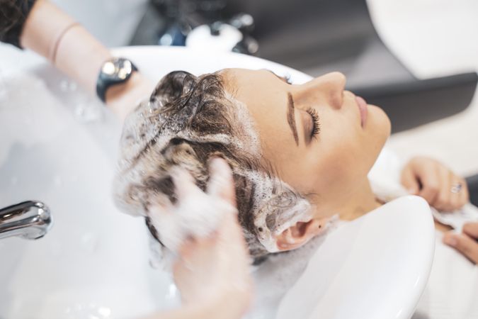 Stylist shampooing hair  of female client
