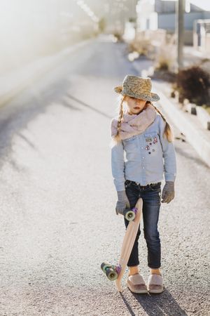Stylish girl with skateboard on street
