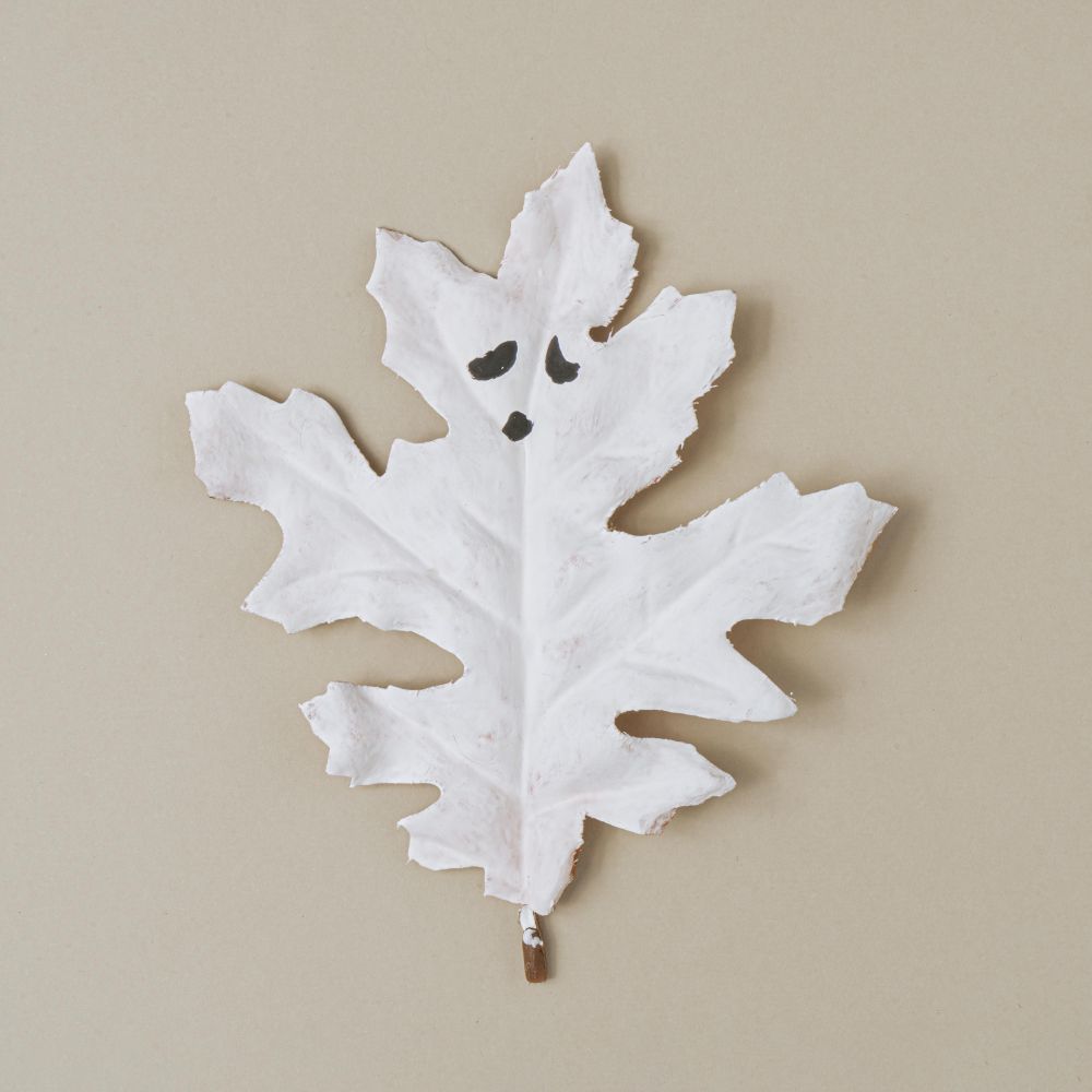Flat lay Halloween background made with autumn leaf painted as ghosts