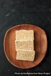 Top view slices of fresh tempeh on wooden plate 4mYeo4