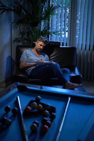 Male employee writing notes in dark office