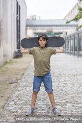 A teenage boy carrying skateboard and smiling 5wXpkm