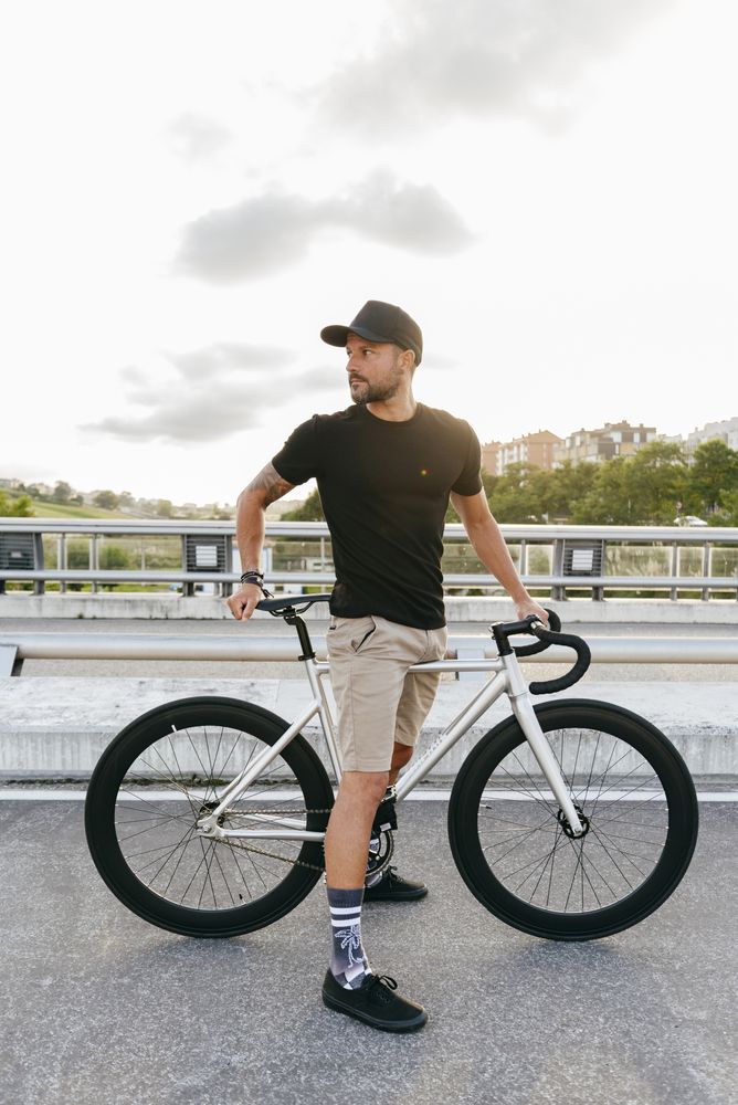 Cheerful man with bicycle standing on footbridge
